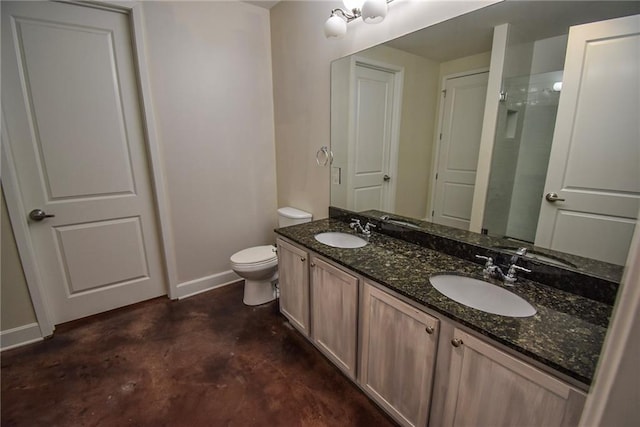 bathroom with double vanity, a sink, toilet, and baseboards