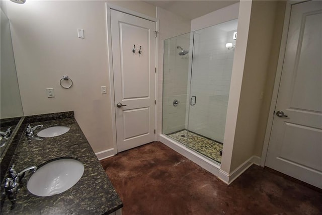 bathroom featuring a sink, a shower stall, baseboards, and double vanity