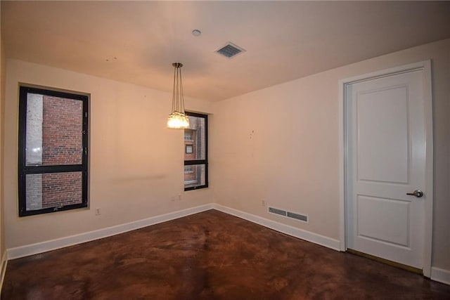 spare room with concrete flooring, visible vents, and baseboards