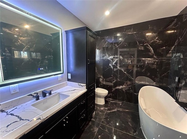 full bathroom featuring marble finish floor, a freestanding tub, vanity, and toilet