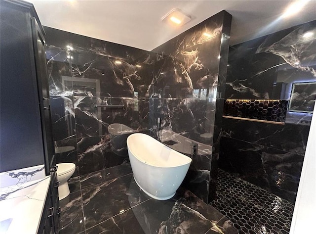 full bathroom featuring stone wall, marble finish floor, and a freestanding tub