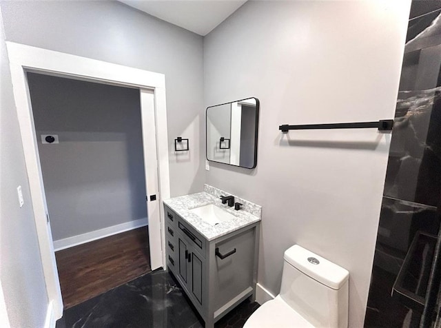 bathroom featuring toilet, baseboards, and vanity