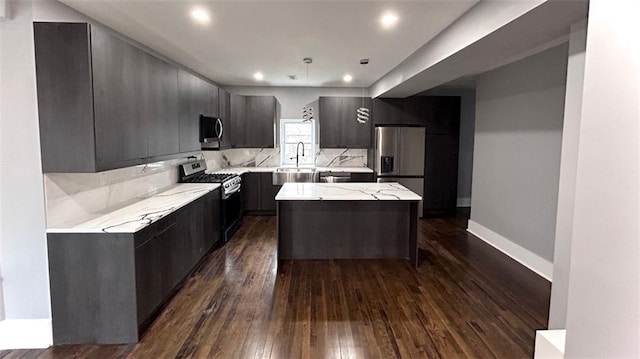 kitchen with dark wood-style floors, backsplash, a center island, stainless steel appliances, and a sink