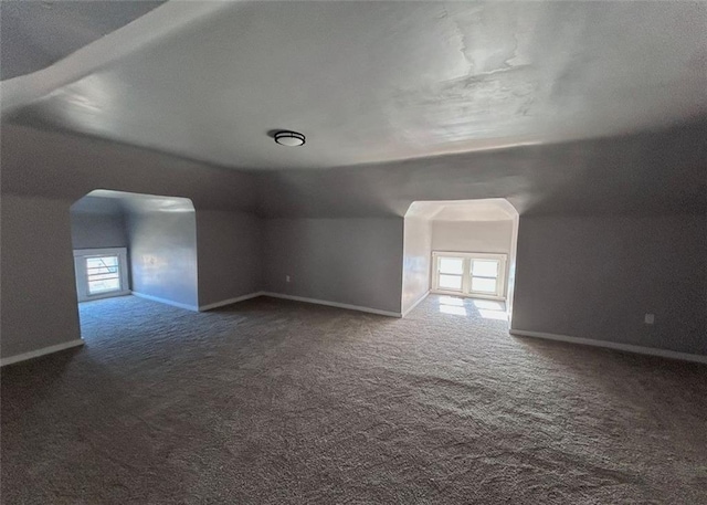 additional living space featuring arched walkways, carpet floors, and baseboards