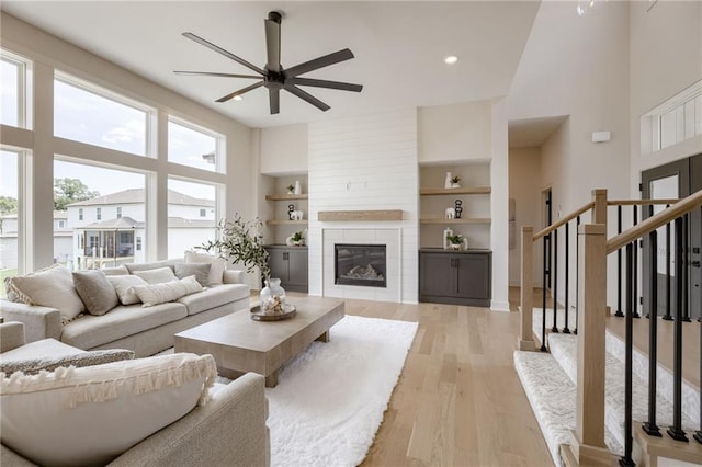 12455 N Arbor Way, Platte City, MO 64079 - living room featuring ceiling fan, a high ceiling, light wood finished floors, built in features, and stairway
