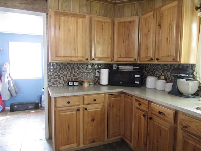 kitchen featuring black microwave, light tile patterned flooring, light countertops, and tasteful backsplash