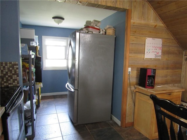 kitchen featuring range, light countertops, wooden walls, baseboards, and freestanding refrigerator