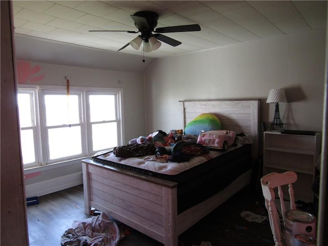 bedroom featuring baseboards, wood finished floors, vaulted ceiling, and a ceiling fan