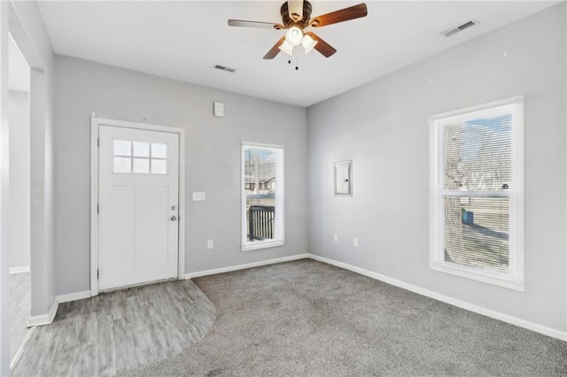 foyer with carpet floors, baseboards, visible vents, and ceiling fan