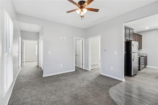 unfurnished bedroom featuring carpet flooring, visible vents, a ceiling fan, baseboards, and freestanding refrigerator