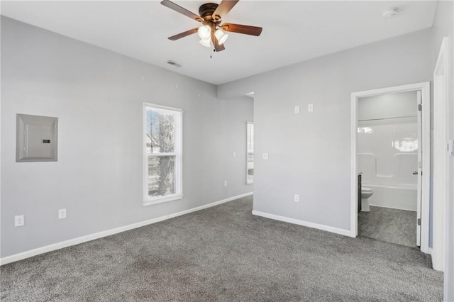 unfurnished bedroom featuring connected bathroom, carpet flooring, visible vents, baseboards, and electric panel