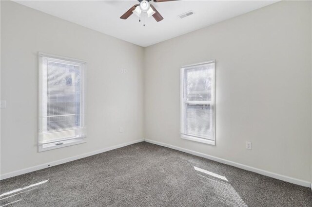 carpeted empty room featuring ceiling fan, visible vents, and baseboards