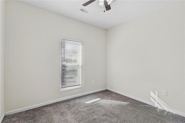 carpeted empty room with baseboards, visible vents, and ceiling fan