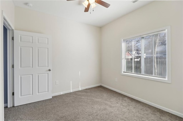 carpeted spare room featuring baseboards and a ceiling fan