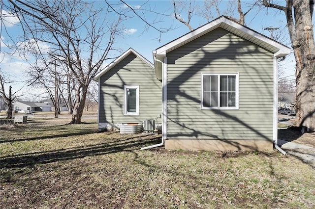 rear view of house with central AC unit and a lawn