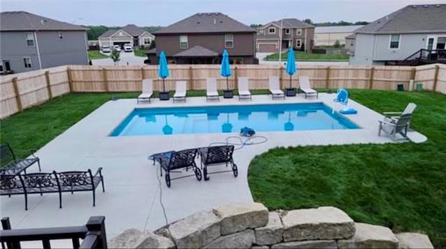 view of swimming pool with a residential view, a patio, a yard, and a fenced backyard