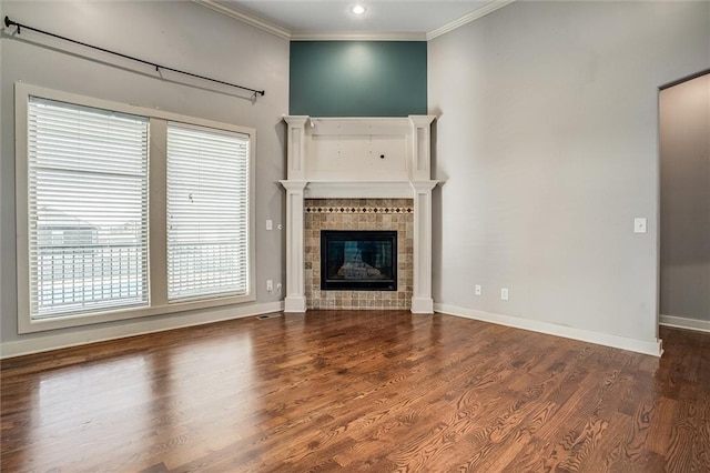 unfurnished living room featuring a fireplace, crown molding, baseboards, and wood finished floors