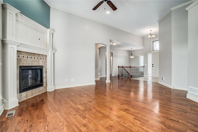 unfurnished living room featuring visible vents, crown molding, baseboards, and wood finished floors