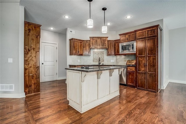 kitchen featuring visible vents, a kitchen breakfast bar, appliances with stainless steel finishes, and dark wood finished floors