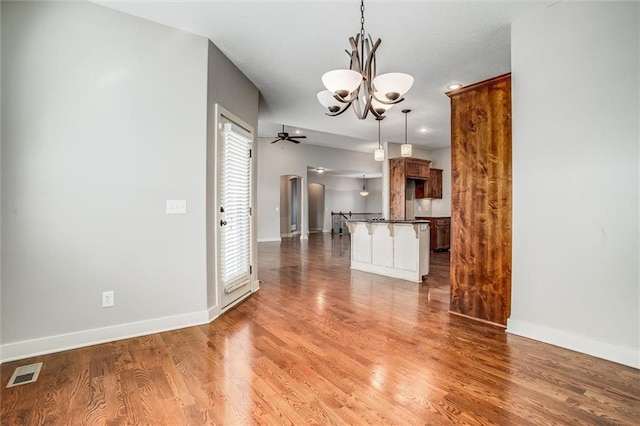 kitchen featuring a breakfast bar area, wood finished floors, visible vents, arched walkways, and dark countertops