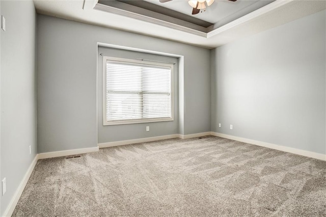 spare room featuring baseboards, a raised ceiling, and carpet flooring