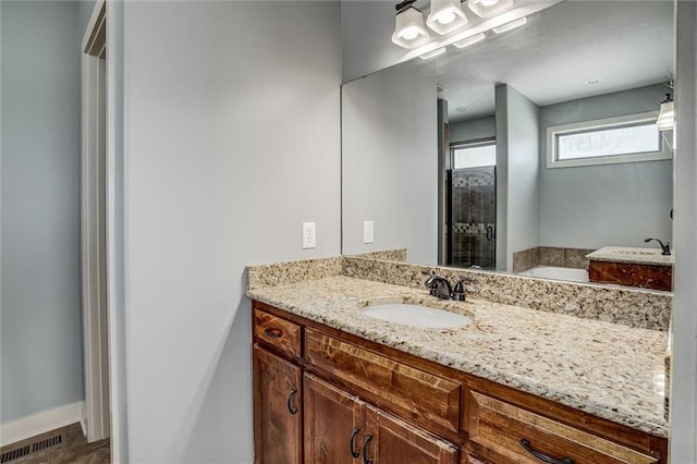 bathroom with visible vents, a garden tub, a stall shower, baseboards, and vanity