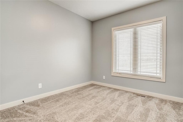 spare room with visible vents, light colored carpet, and baseboards