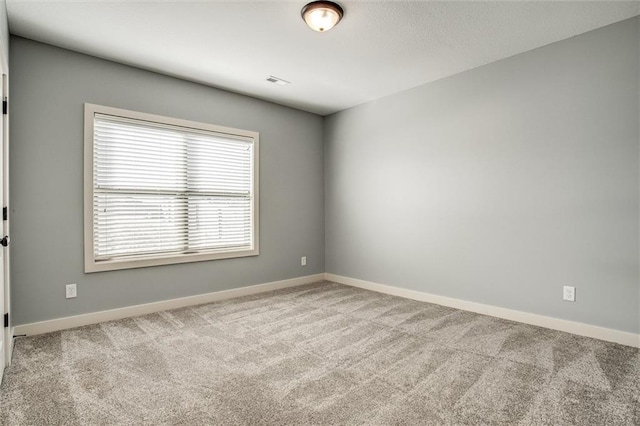 carpeted empty room with visible vents and baseboards