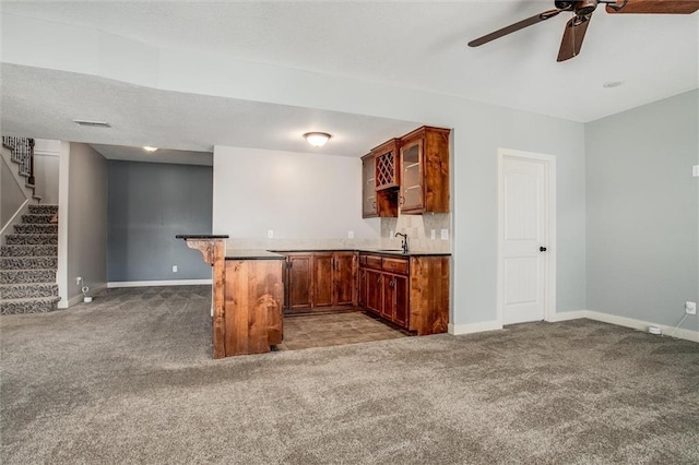 kitchen featuring a sink, glass insert cabinets, light carpet, and a peninsula