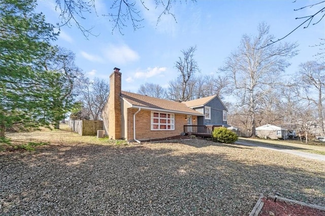 view of side of property featuring brick siding, fence, central air condition unit, a chimney, and a deck