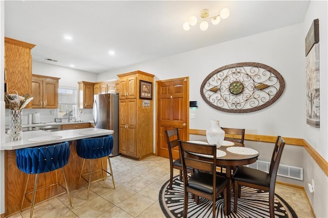 kitchen featuring visible vents, appliances with stainless steel finishes, a peninsula, light countertops, and a kitchen bar