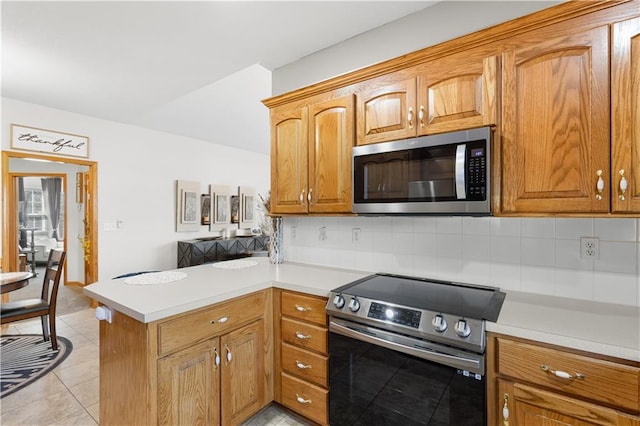 kitchen with a peninsula, backsplash, stainless steel appliances, and light countertops