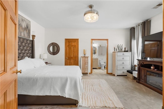 bedroom with ensuite bath, visible vents, and light colored carpet