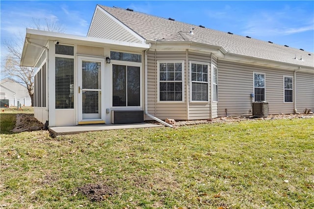 back of property with central AC unit, a sunroom, roof with shingles, a lawn, and a patio area