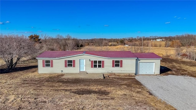 view of front of home featuring metal roof, driveway, and an attached garage