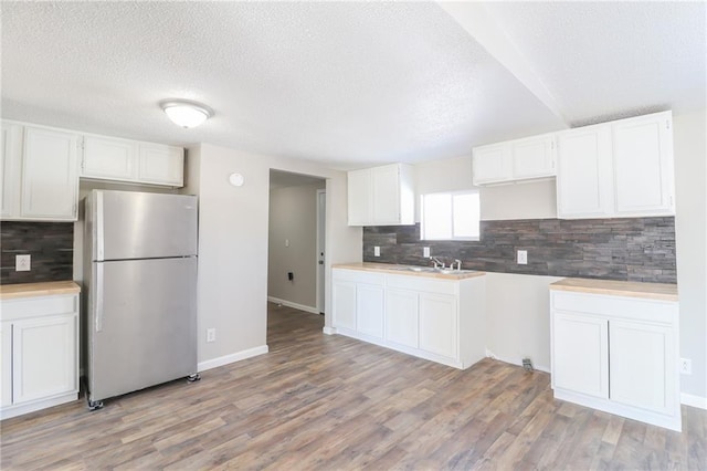 kitchen featuring light wood-style flooring, white cabinetry, and freestanding refrigerator