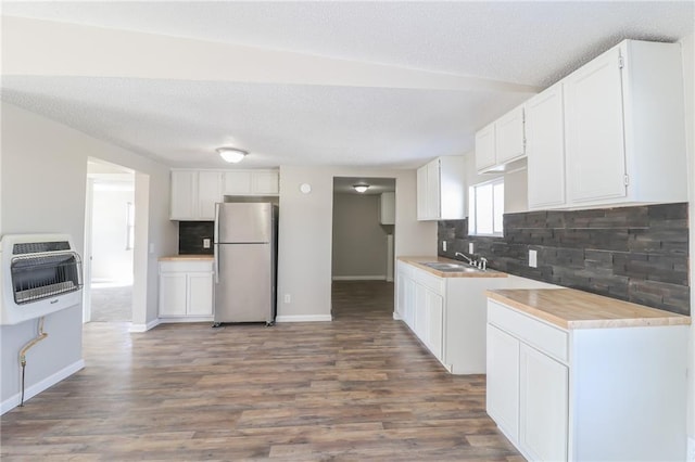 kitchen with heating unit, light countertops, backsplash, freestanding refrigerator, and a sink