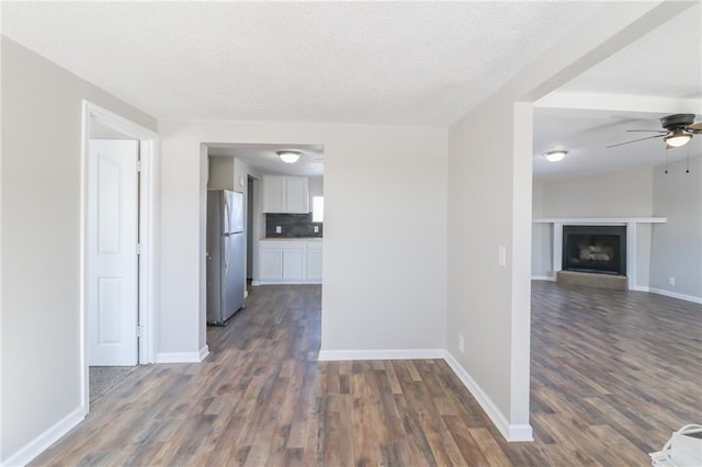 interior space featuring dark wood-style flooring, a textured ceiling, and baseboards