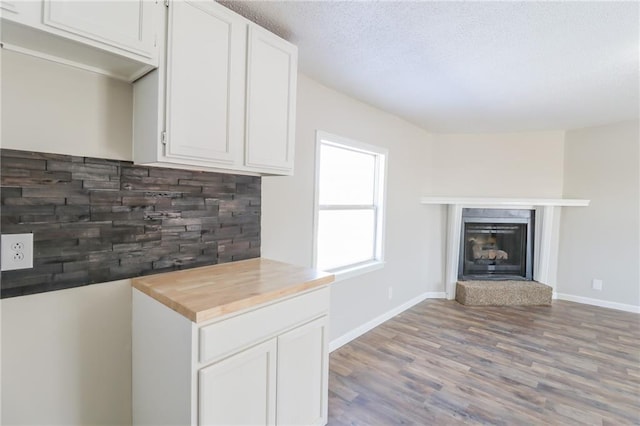 kitchen with tasteful backsplash, white cabinets, and a fireplace with raised hearth