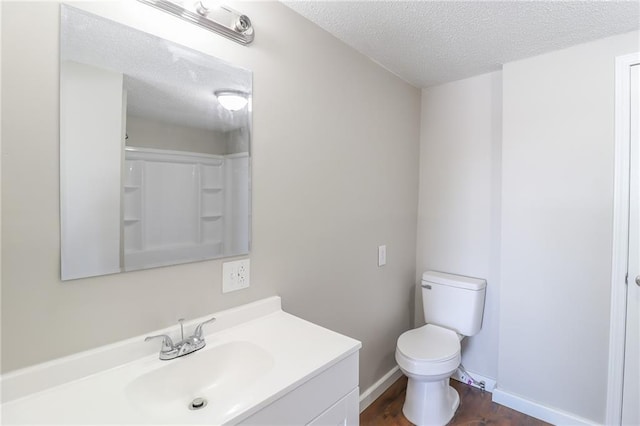 bathroom featuring a textured ceiling, toilet, vanity, baseboards, and a shower