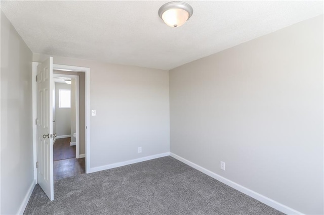 empty room with baseboards and dark colored carpet