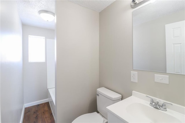 full bathroom with toilet, a textured ceiling, vanity, wood finished floors, and baseboards