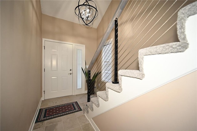 foyer entrance featuring a chandelier, tile patterned flooring, stairway, and baseboards