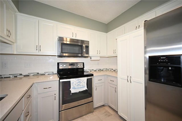 kitchen featuring white cabinets, backsplash, stainless steel appliances, and light countertops