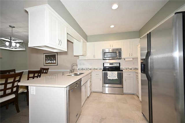 kitchen featuring white cabinets, a sink, stainless steel appliances, light countertops, and backsplash