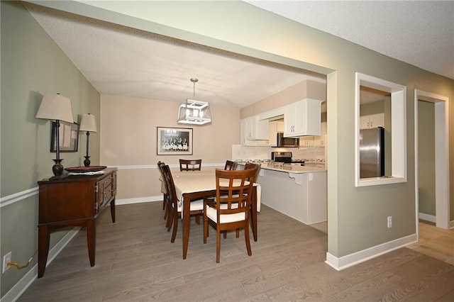 dining area featuring light wood finished floors and baseboards