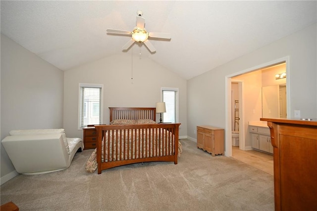 bedroom featuring lofted ceiling, baseboards, ensuite bath, and light colored carpet