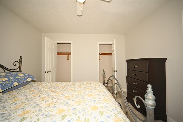 bedroom featuring ceiling fan, a textured ceiling, baseboards, and multiple closets