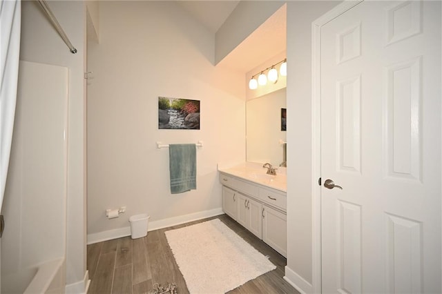 full bathroom featuring baseboards, wood finished floors, and vanity