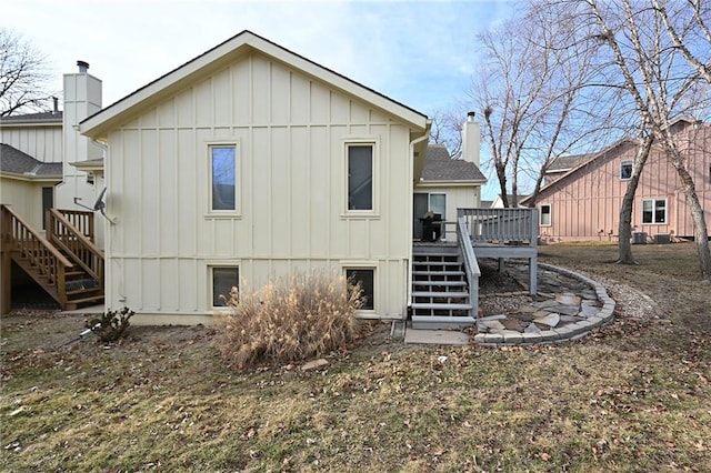 rear view of house featuring stairs, a chimney, a deck, and board and batten siding